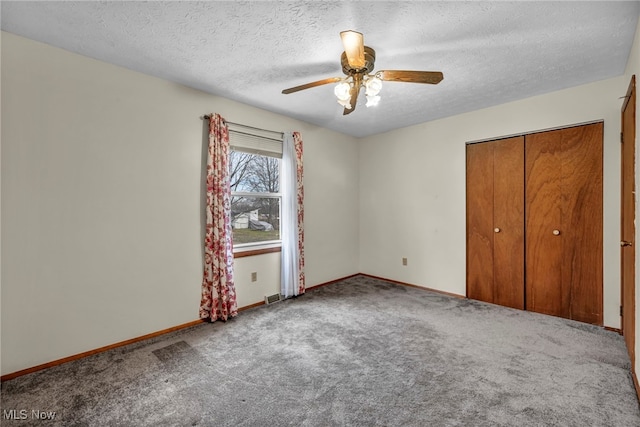 unfurnished bedroom with carpet floors, a textured ceiling, baseboards, and a closet