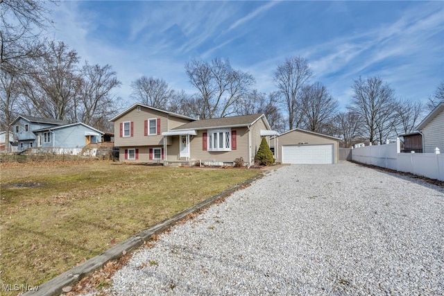 view of front of house with a garage, fence, a front lawn, and an outbuilding