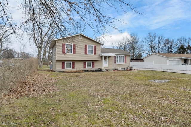 tri-level home with fence and a front yard