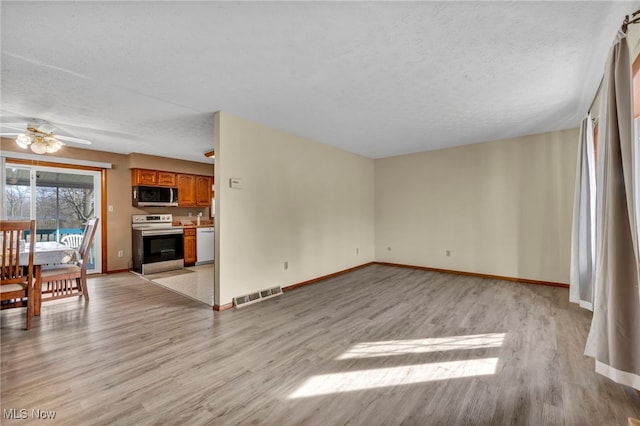 unfurnished living room with light wood-style floors, baseboards, visible vents, and a textured ceiling