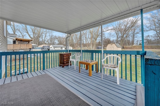 wooden terrace with a shed, a lawn, an outdoor structure, and fence