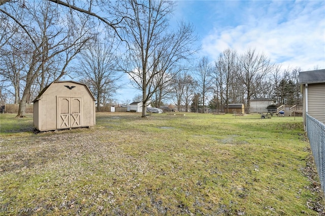 view of yard featuring a shed, fence, and an outbuilding