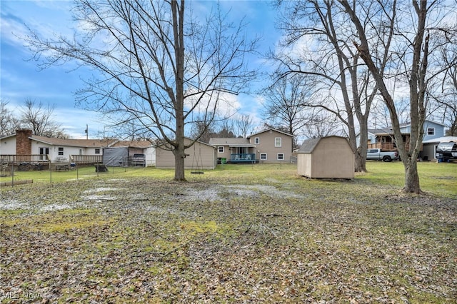 view of yard featuring a storage unit, an outdoor structure, fence, and a residential view