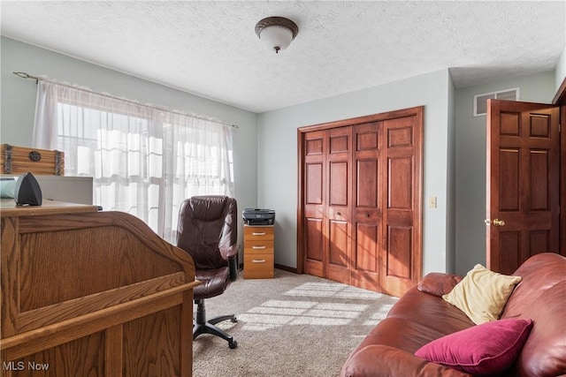 office featuring visible vents, light colored carpet, and a textured ceiling