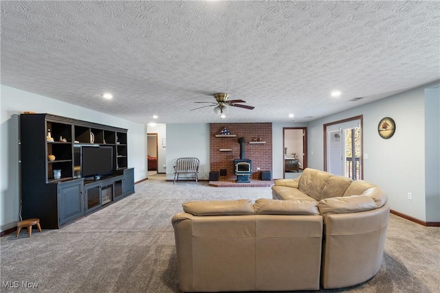 living room featuring baseboards, a wood stove, recessed lighting, a textured ceiling, and light carpet