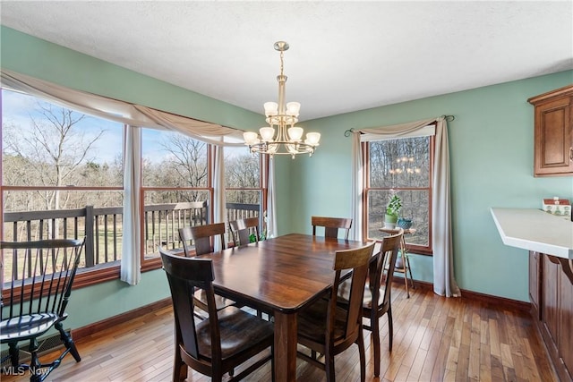 dining room featuring light wood finished floors, a chandelier, and baseboards