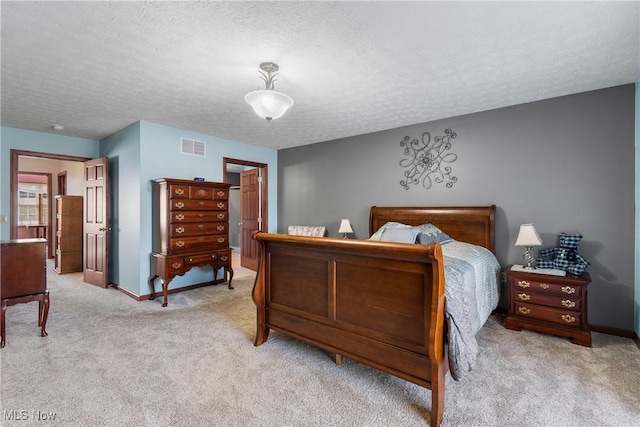 bedroom with carpet flooring, a textured ceiling, baseboards, and visible vents