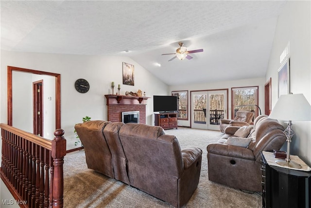 living room featuring a textured ceiling, carpet, a fireplace, lofted ceiling, and ceiling fan