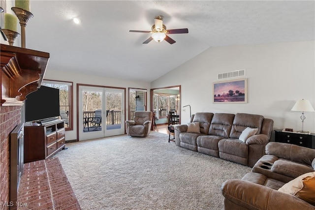 carpeted living room featuring visible vents, high vaulted ceiling, ceiling fan, and a fireplace