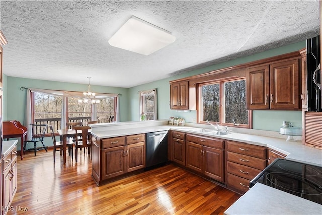 kitchen with a sink, a peninsula, light countertops, and stainless steel dishwasher