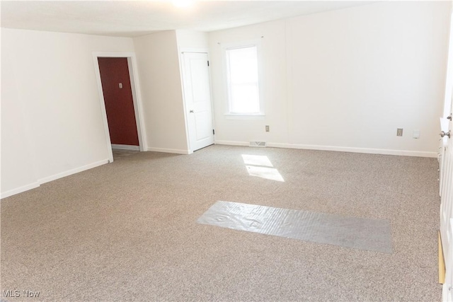 carpeted spare room featuring visible vents and baseboards