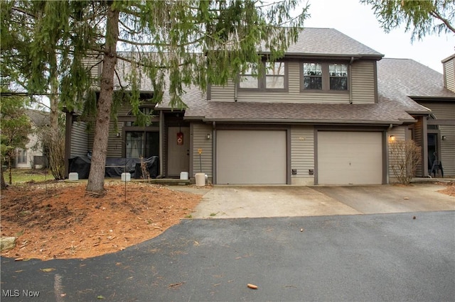 view of front of property with an attached garage, a chimney, aphalt driveway, and roof with shingles