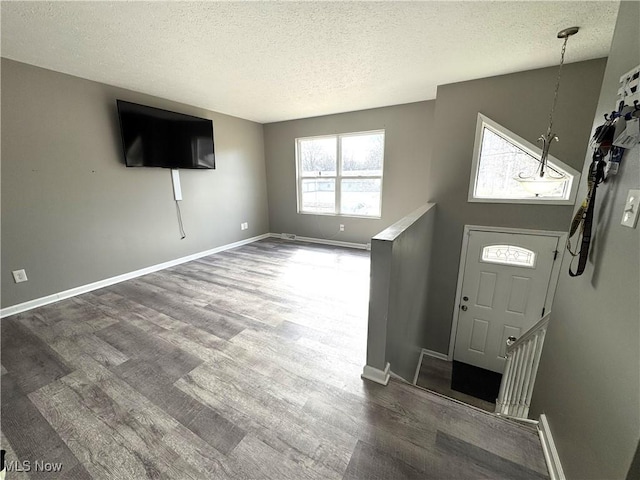 entryway with a textured ceiling, baseboards, and wood finished floors