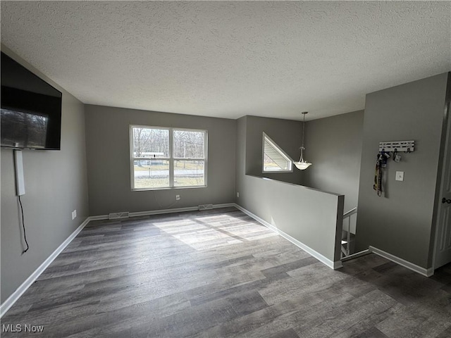 interior space with a textured ceiling, baseboards, and dark wood-type flooring