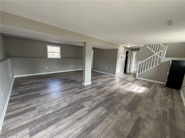 interior space featuring a textured ceiling, stairway, wood finished floors, and baseboards