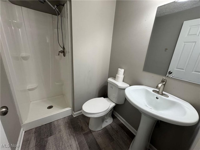 full bath featuring a stall shower, baseboards, toilet, and wood finished floors