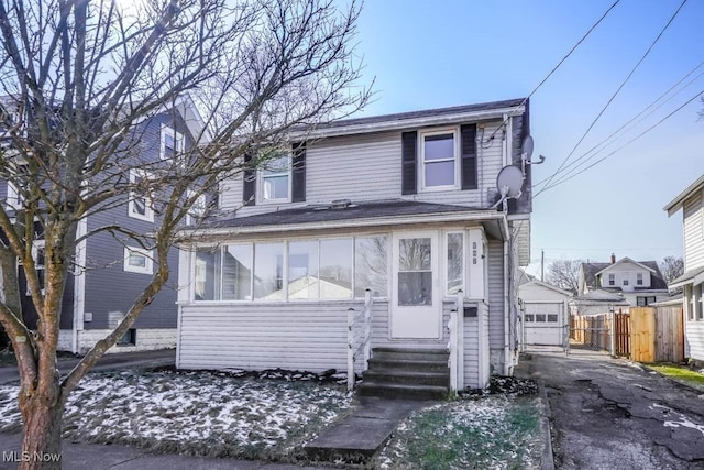 view of front of home with entry steps, fence, a garage, driveway, and an outdoor structure