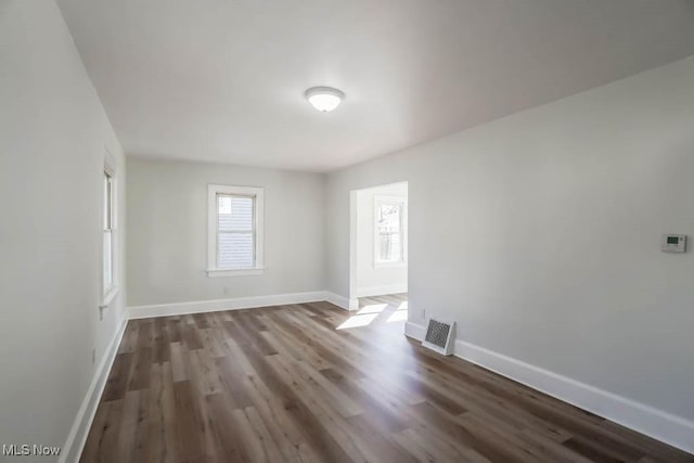 spare room featuring dark wood-style floors, visible vents, and baseboards