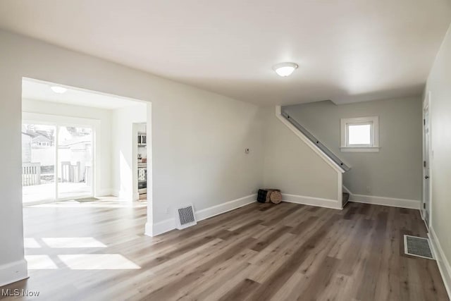 basement with stairs, visible vents, baseboards, and wood finished floors