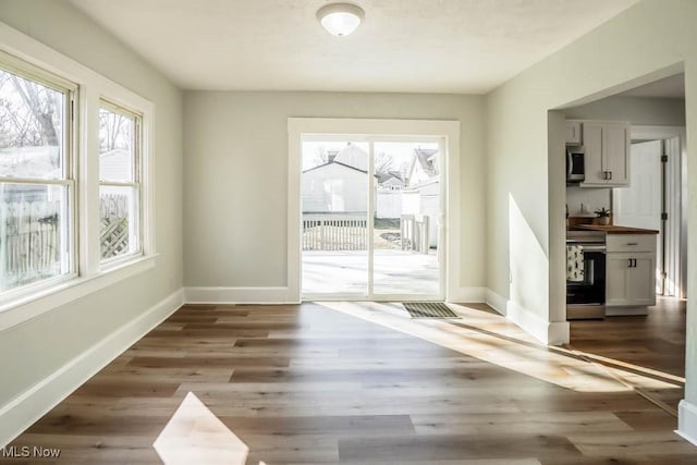 doorway with a healthy amount of sunlight, visible vents, baseboards, and wood finished floors