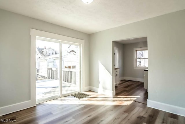 doorway with a textured ceiling, baseboards, and wood finished floors