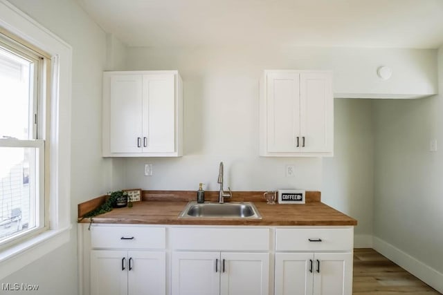 kitchen with white cabinets, a sink, and baseboards