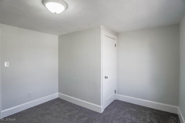 bonus room featuring baseboards, dark colored carpet, and a textured ceiling