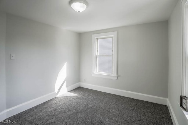 empty room featuring dark carpet and baseboards