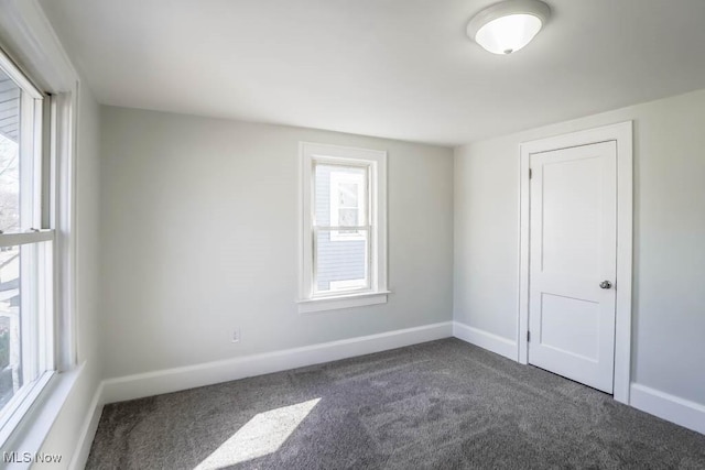 empty room with dark carpet and baseboards