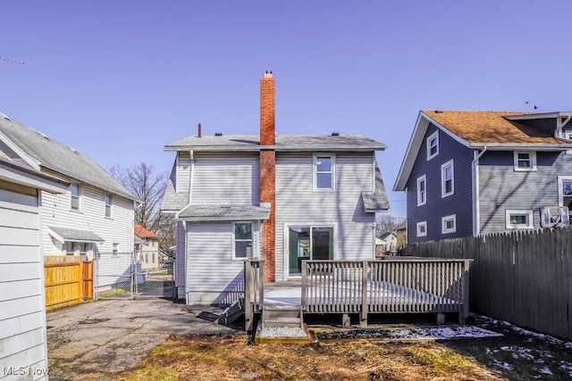 rear view of property with a gate, a fenced backyard, a chimney, and a wooden deck