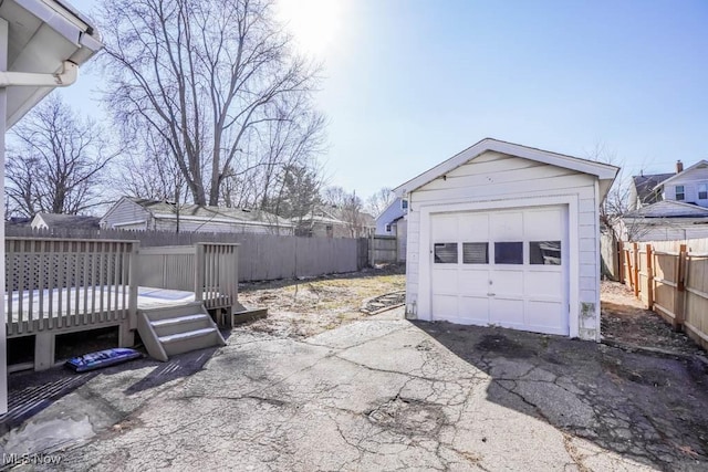 detached garage featuring driveway and fence