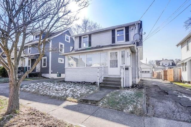 view of front facade featuring entry steps, fence, a garage, driveway, and an outdoor structure