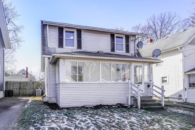 view of front facade featuring a sunroom, fence, and central AC