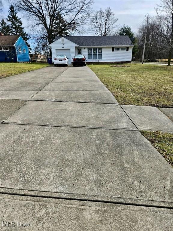 view of front of home with an attached garage, a front lawn, and concrete driveway