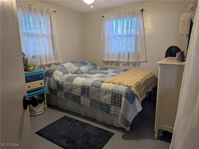 bedroom with a textured ceiling and multiple windows