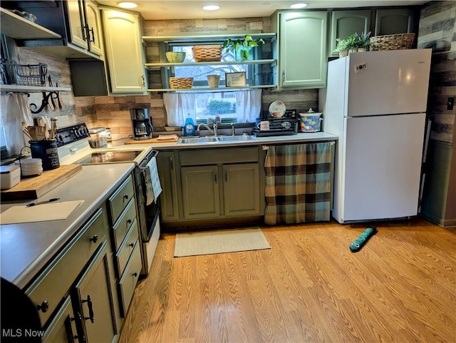 kitchen with light wood finished floors, electric range, freestanding refrigerator, open shelves, and a sink