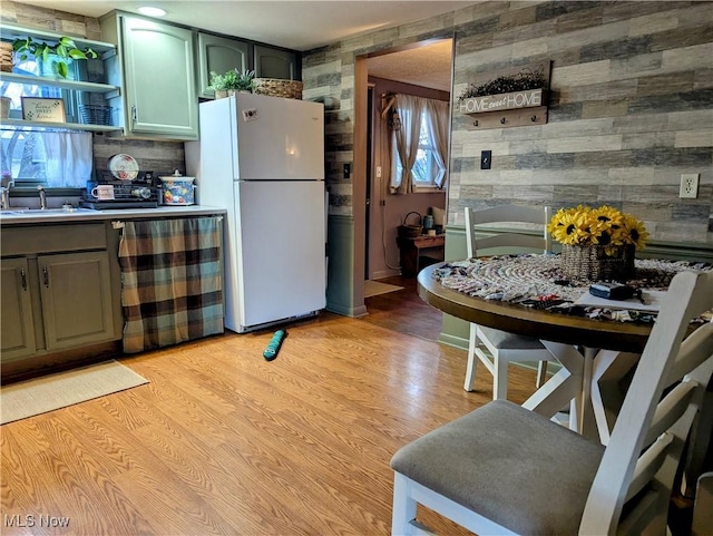 kitchen featuring dishwasher, light wood-style flooring, freestanding refrigerator, light countertops, and a sink