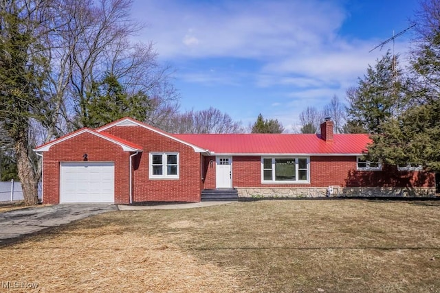 ranch-style house with brick siding, a chimney, an attached garage, metal roof, and driveway