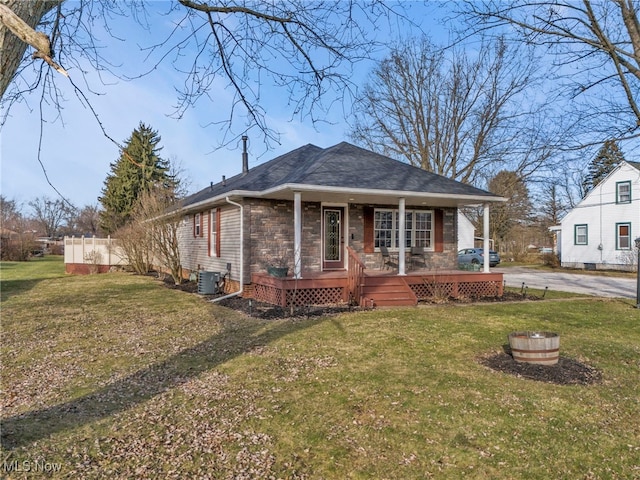 bungalow-style home featuring central AC unit, roof with shingles, covered porch, and a front lawn