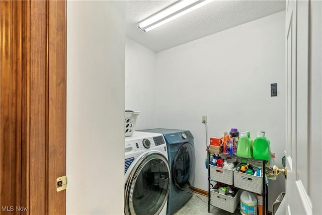 washroom featuring laundry area, washer and clothes dryer, a textured ceiling, and tile patterned floors