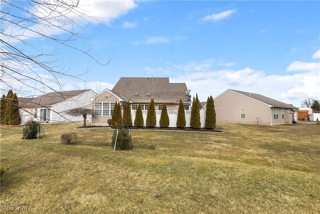 rear view of house with a shingled roof and a yard