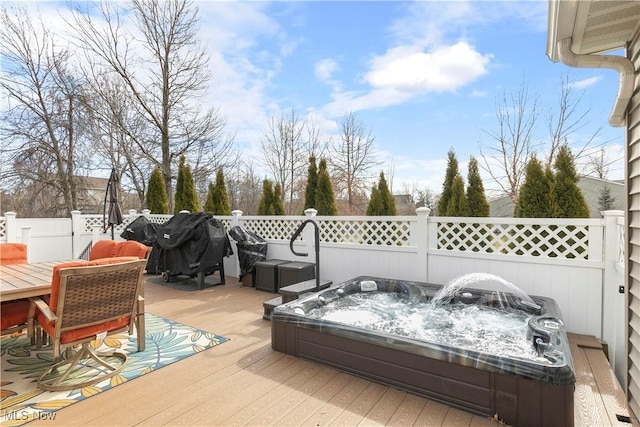 deck with an outdoor hot tub and fence