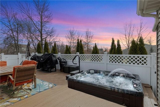 view of patio with fence, a wooden deck, and a hot tub