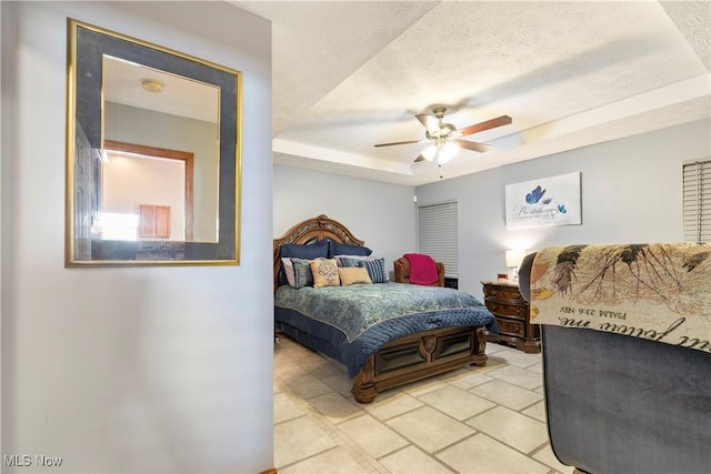 bedroom featuring ceiling fan, a tray ceiling, and a textured ceiling