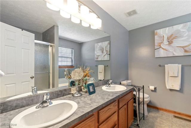 full bath with visible vents, a sink, a shower stall, and a textured ceiling