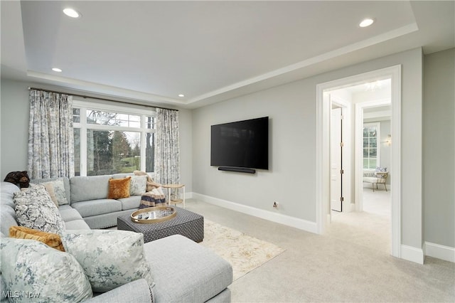 living area with light colored carpet, baseboards, a raised ceiling, and recessed lighting