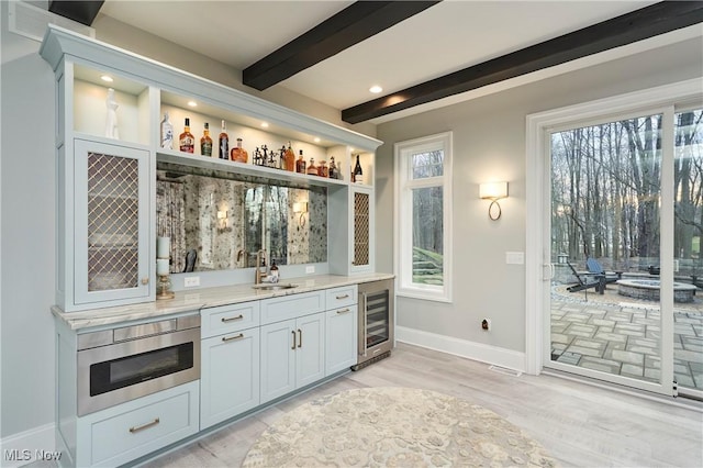 bar featuring wine cooler, stainless steel microwave, indoor wet bar, a sink, and beam ceiling