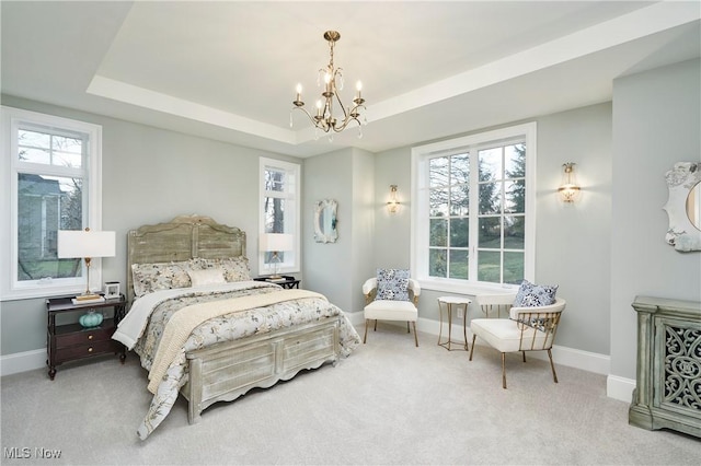 bedroom featuring carpet, a raised ceiling, a notable chandelier, and baseboards