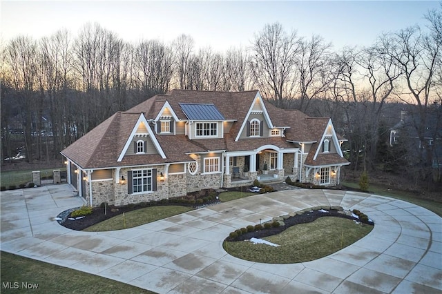 view of front of house with stone siding, curved driveway, and a front yard