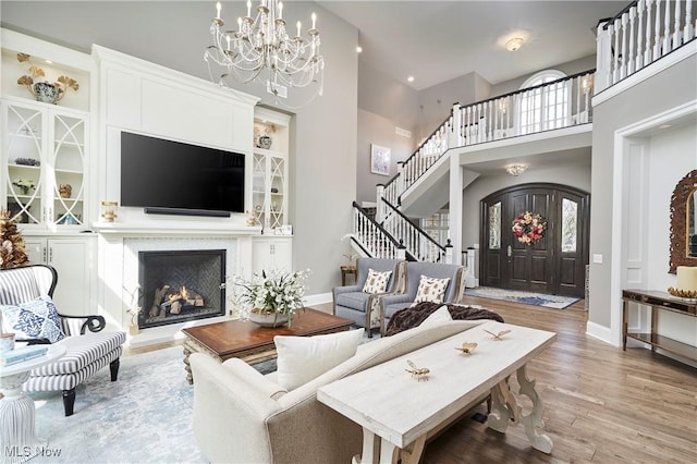 living room with baseboards, a lit fireplace, light wood finished floors, and stairs